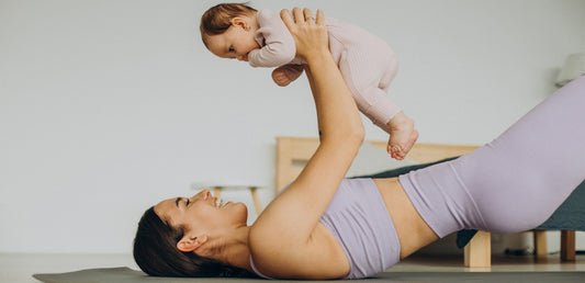 The woman appears relaxed and happy, engaging in playful interaction with her baby, symbolizing postnatal bonding and fitness. The image highlights comfort, wellness, and the joy of motherhood.